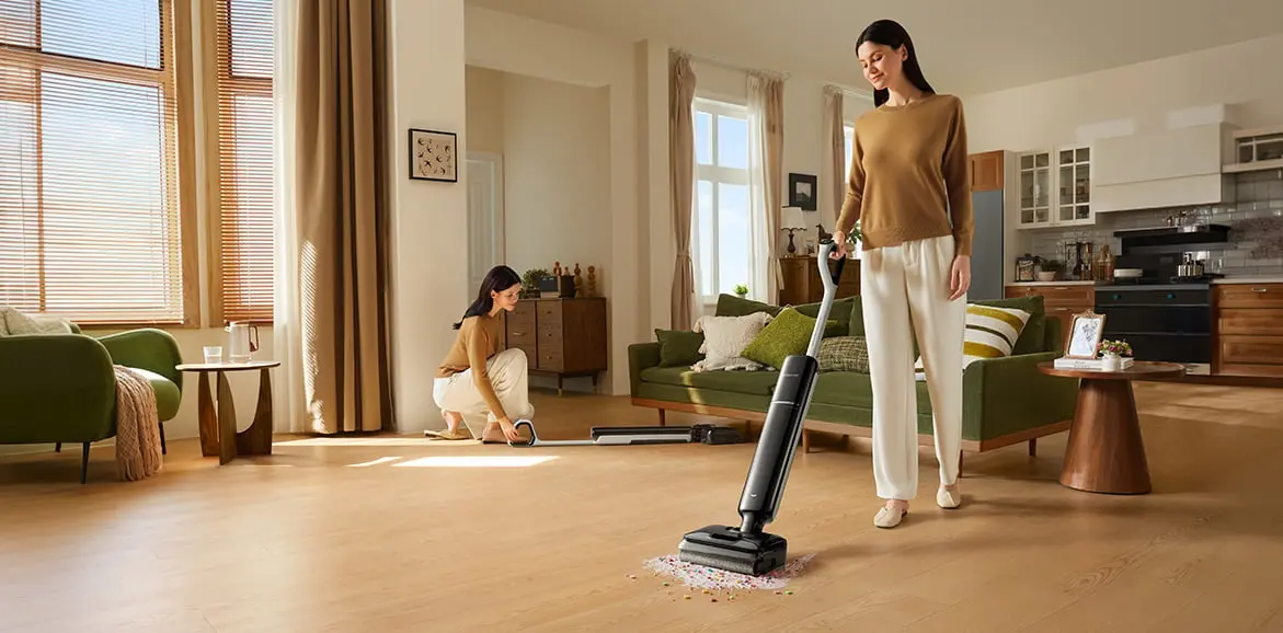 A woman in a bright outfit cleaning a living room with the Dreame G12 Pro vacuum cleaner