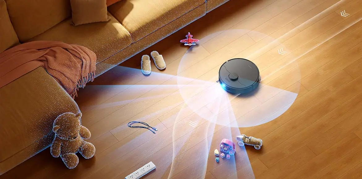 Melns robots putekļu sūcējs skenē šķēršļus uz koka grīdas netālu no dīvāna